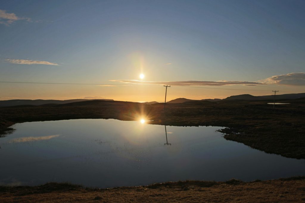 Wireless tower in a sunset photo with pond in foreground