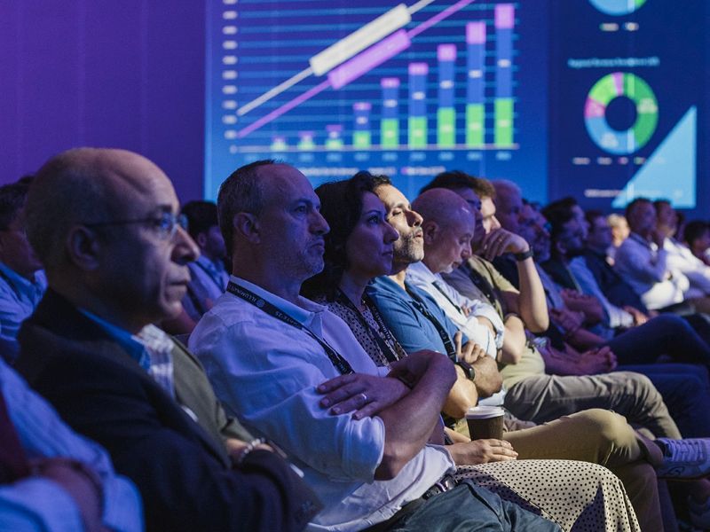 People in audience at a conference in dark lighting